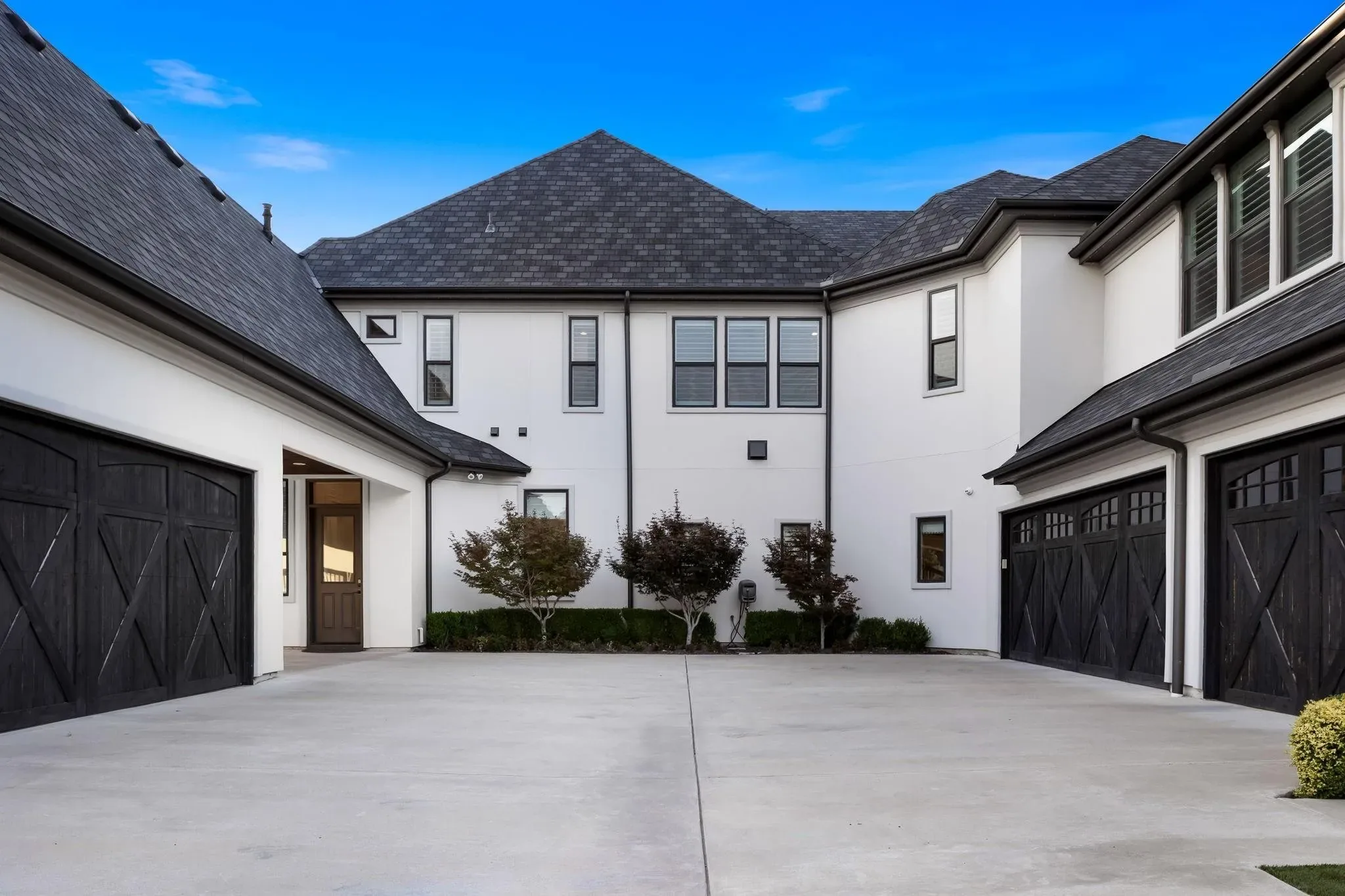 Motor court between two wings with dark carriage-style garage doors on both sides and a side entry door at Craig Ranch, McKinney