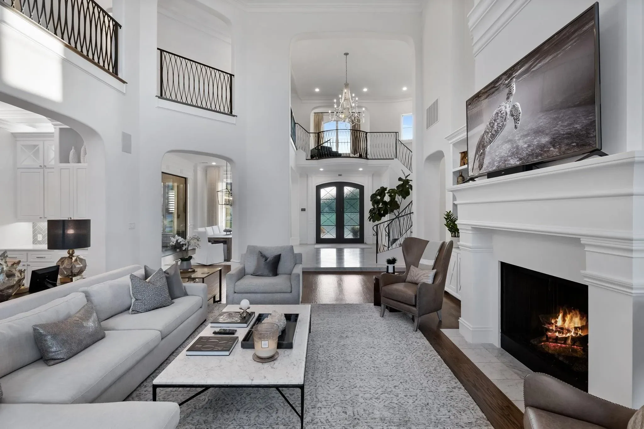 Two-story living room with an iron-railed balcony above and a view through to the arched front doors at Craig Ranch, McKinney