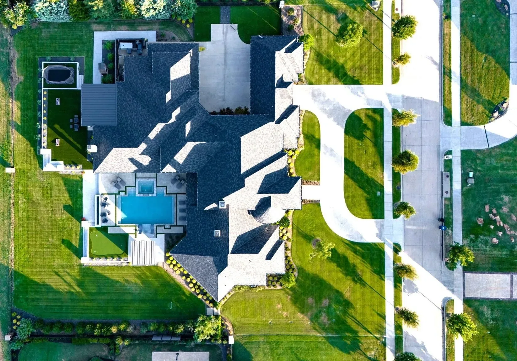 Overhead drone view of a large home showing its roof plan, pool, side drive and front walk at Craig Ranch, McKinney