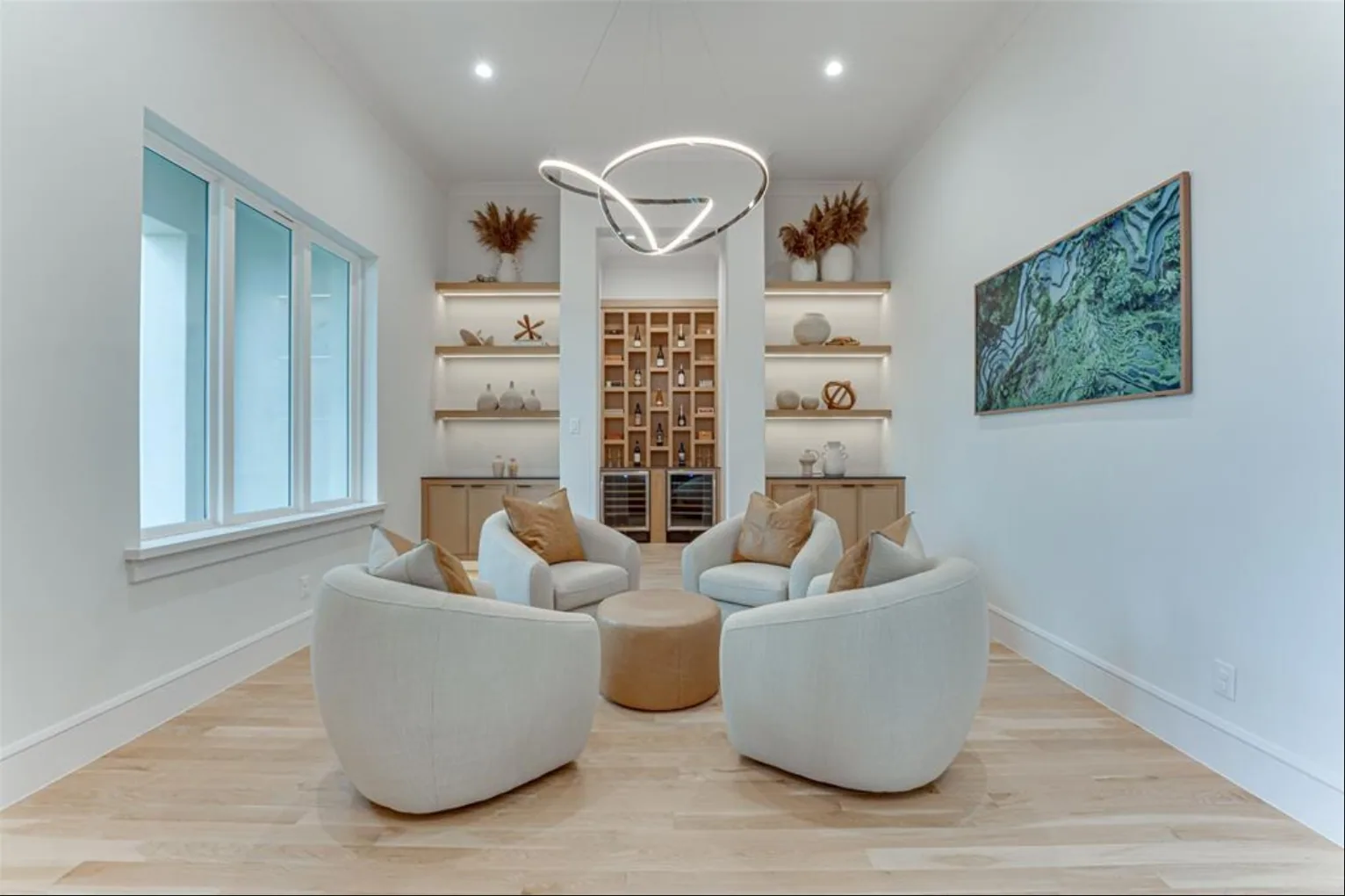 Sitting room with four round lounge chairs under a ring pendant and lit open shelving around a wine niche at Fairways of Heath Crossing