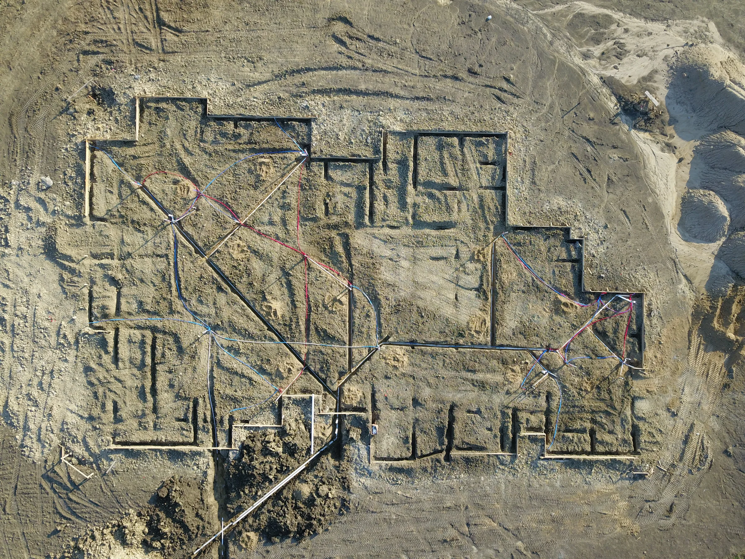 Overhead drone view of foundation trenches dug in the dirt, tracing the outline of the house before the pour
