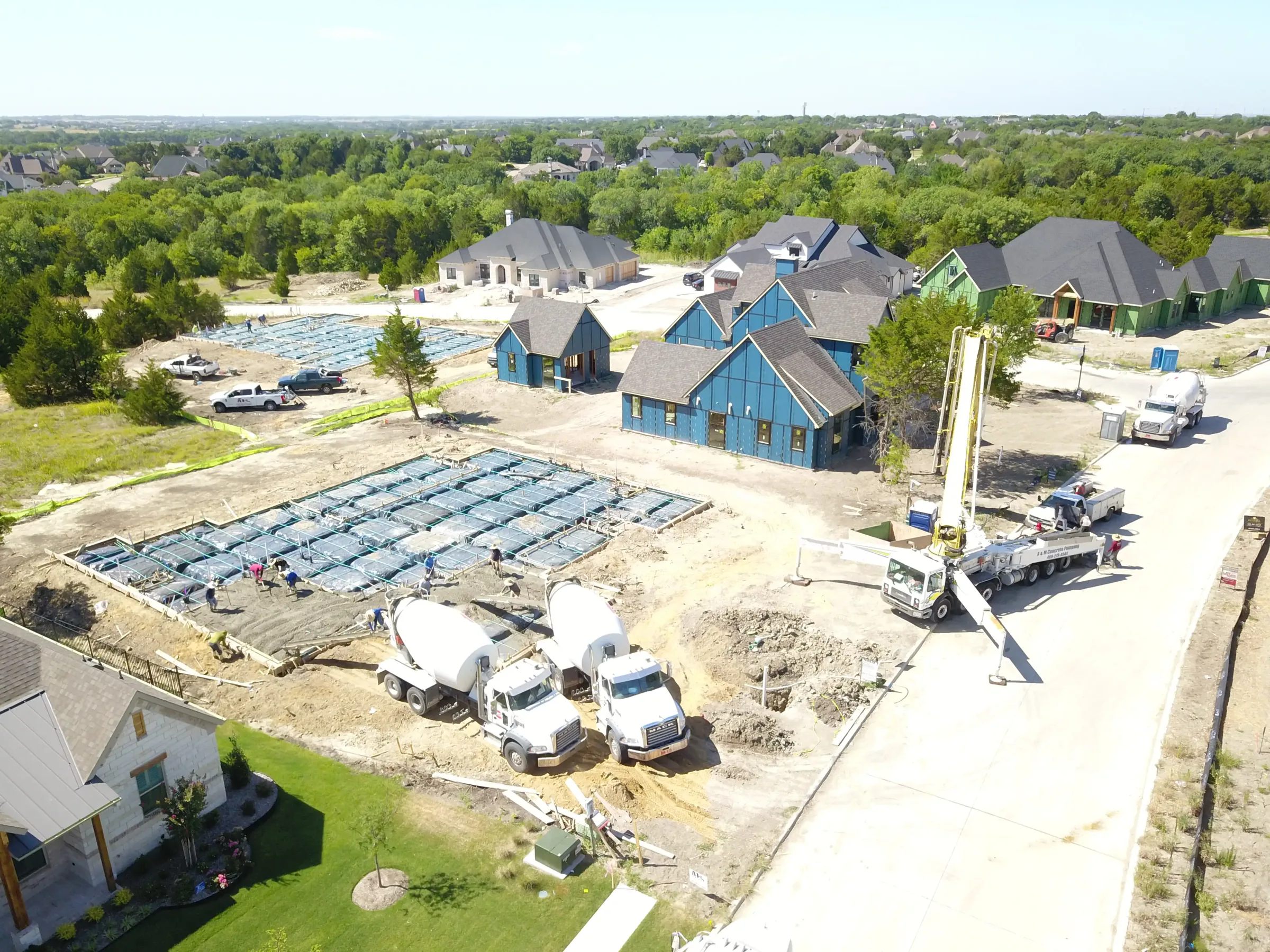 Aerial view of a custom home site across the lot, in daylight on a job site