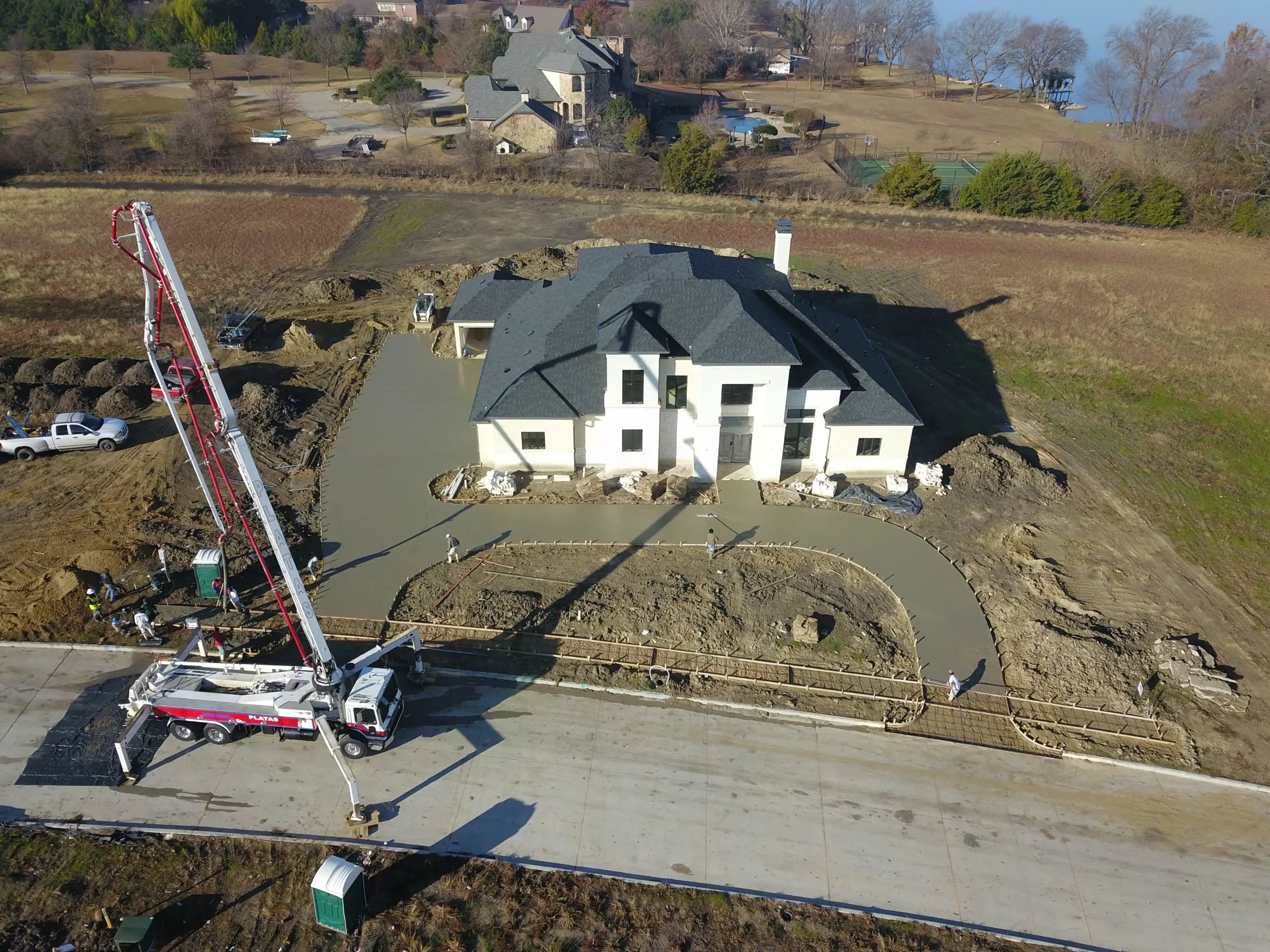 Aerial view of a custom home site looking down the drive, mid-build on a job site