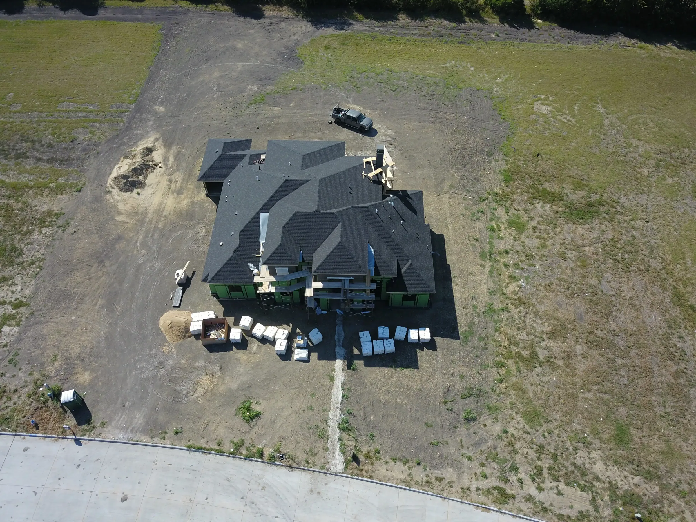 Aerial view of a custom home site across the lot, mid-build on a job site