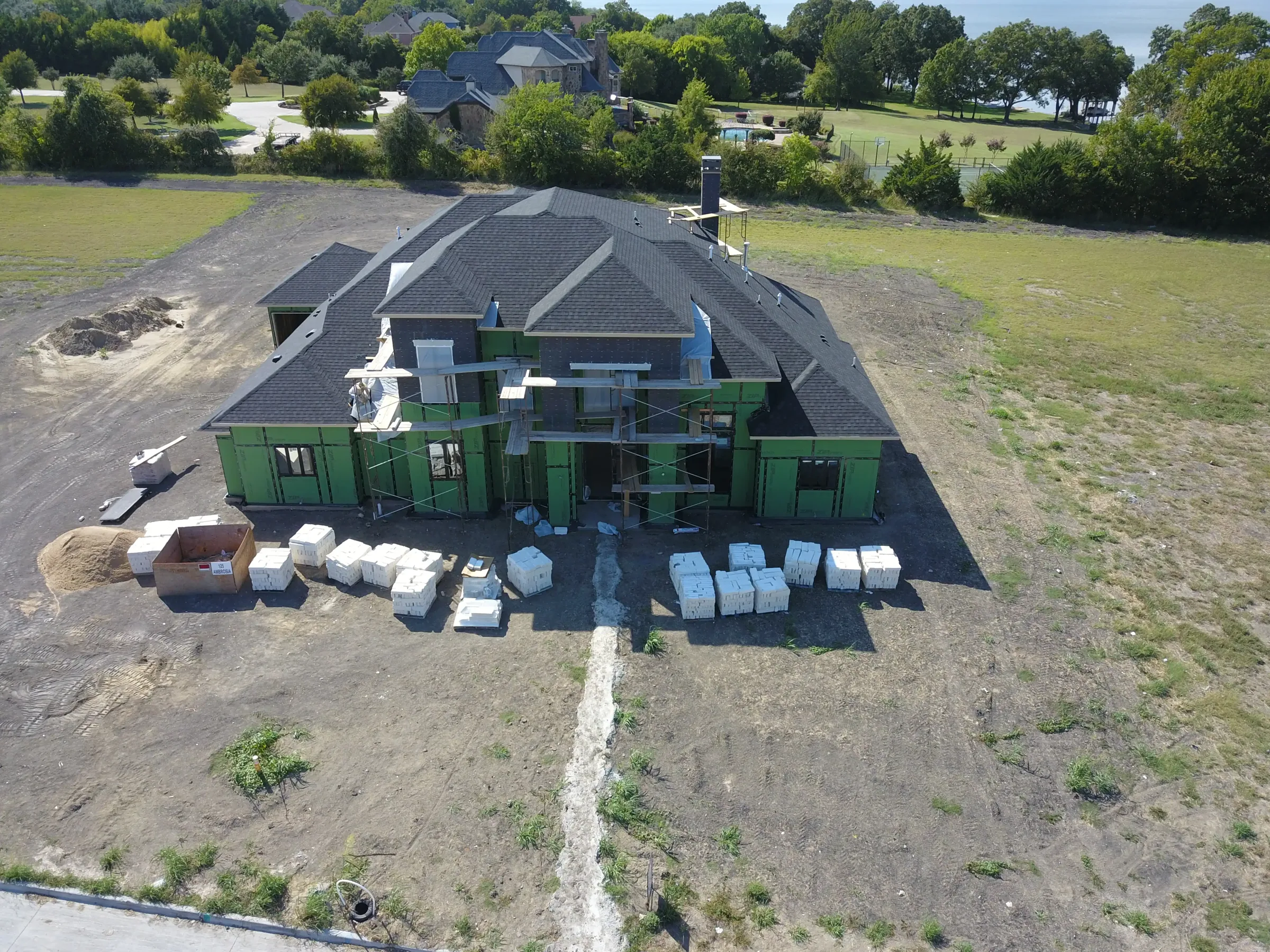 Aerial view of a custom home site from the rear of the property, mid-build on a job site