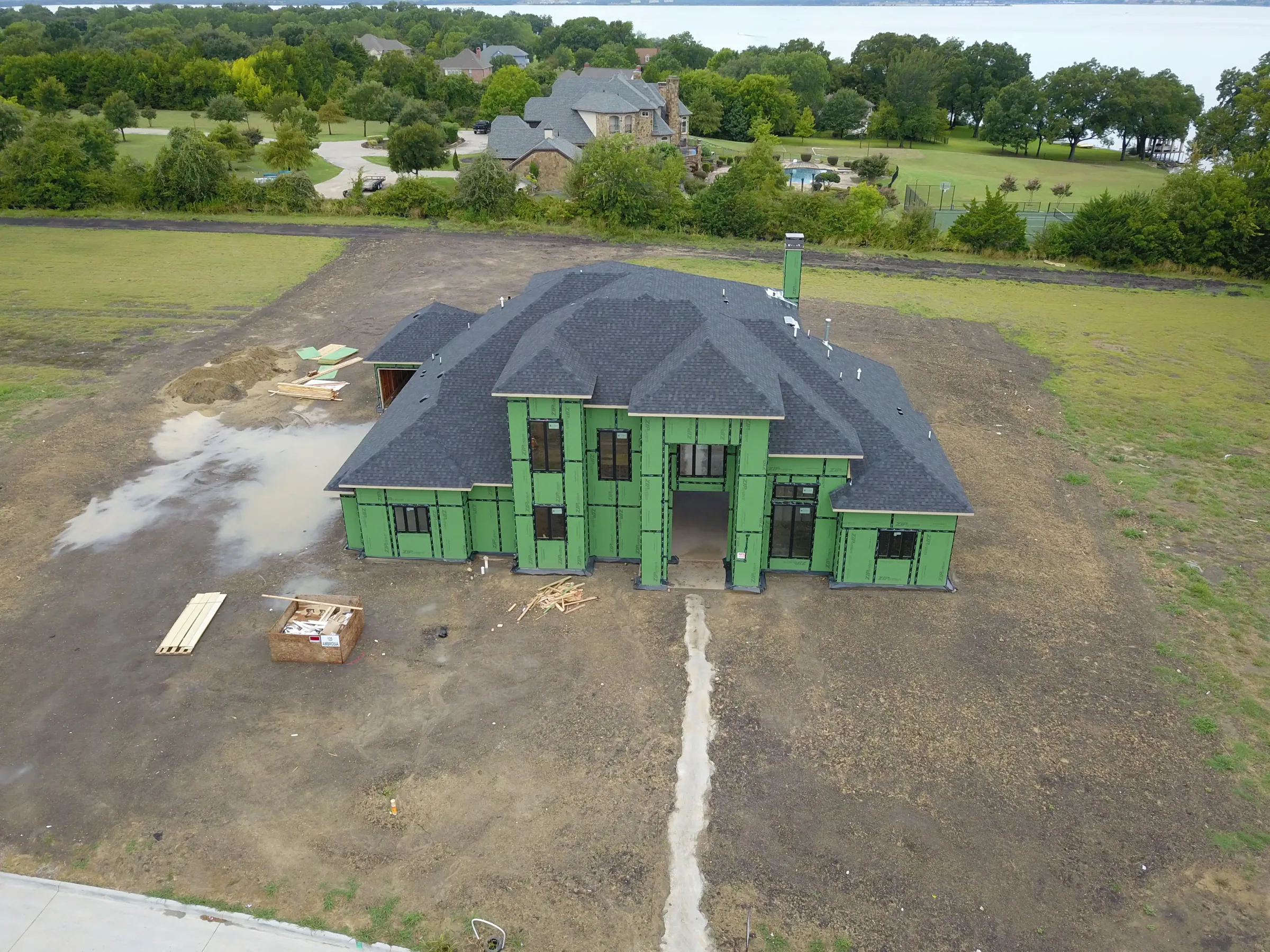 Aerial view of a custom home site across the lot, from a second position on a job site