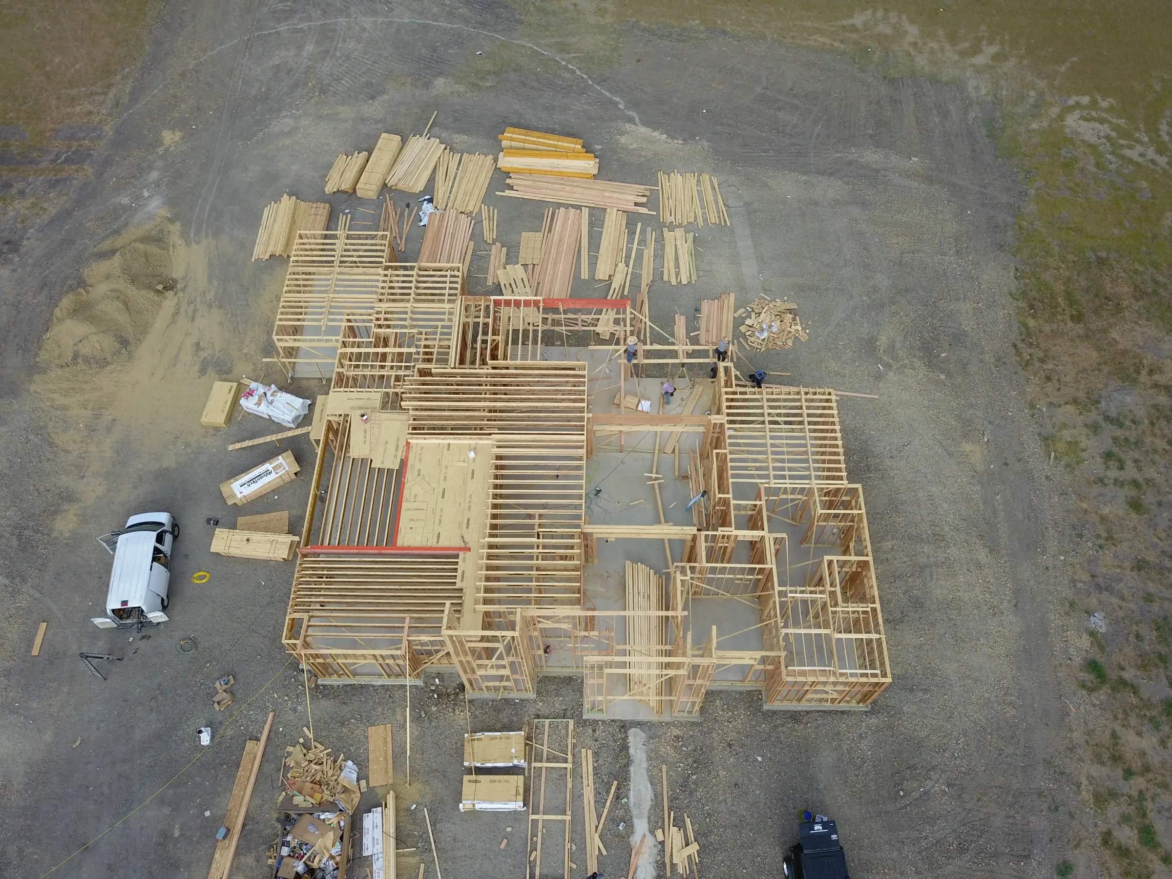 Aerial view of a custom home site looking down the drive, under work lights on a job site