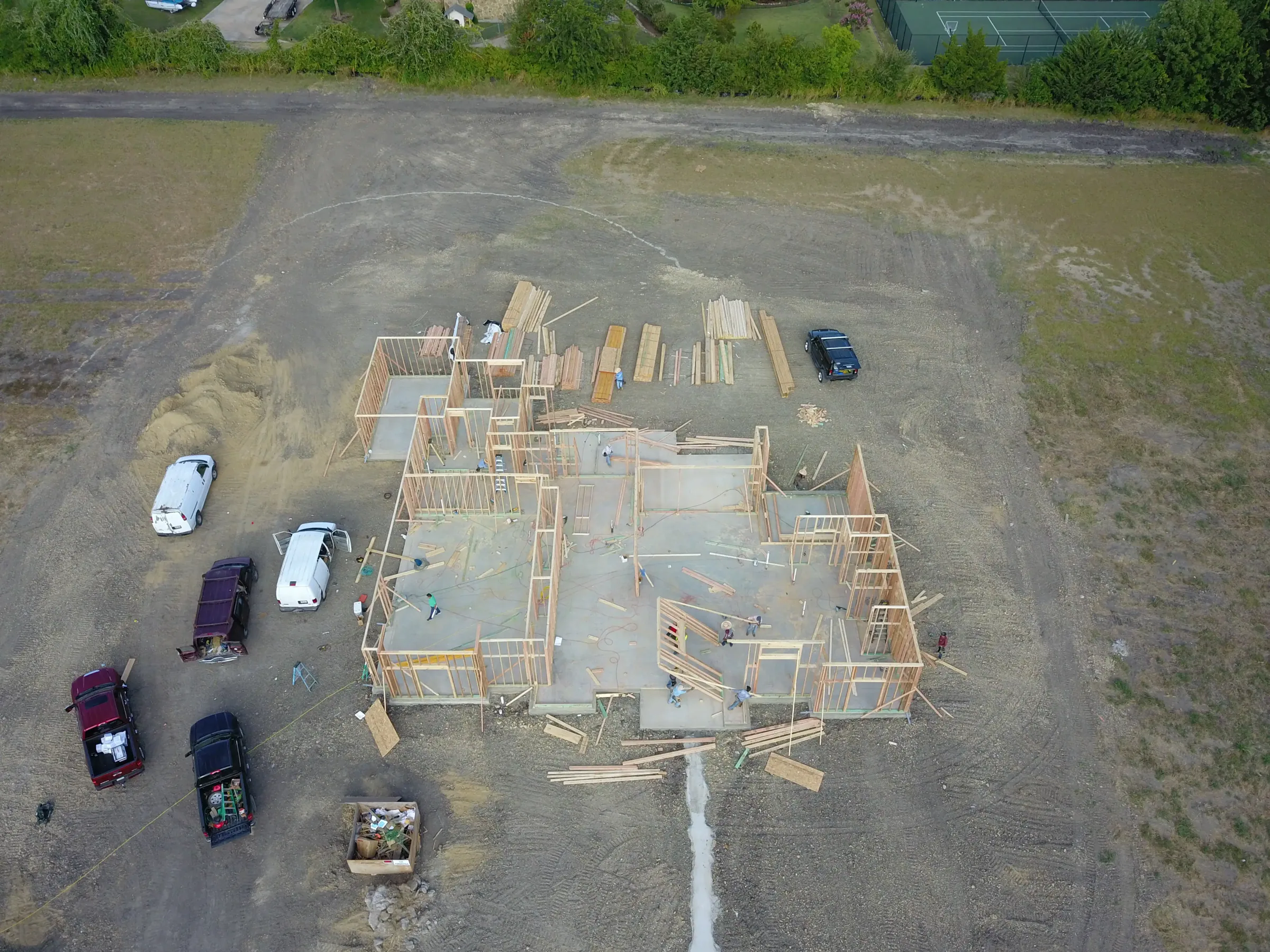 Aerial view of a custom home site from the rear of the property, under work lights on a job site