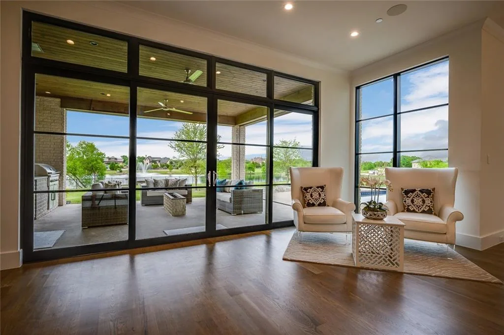 Sitting area beside a full-height black-framed glass wall opening to a covered patio in Ridge Lakes of Heath