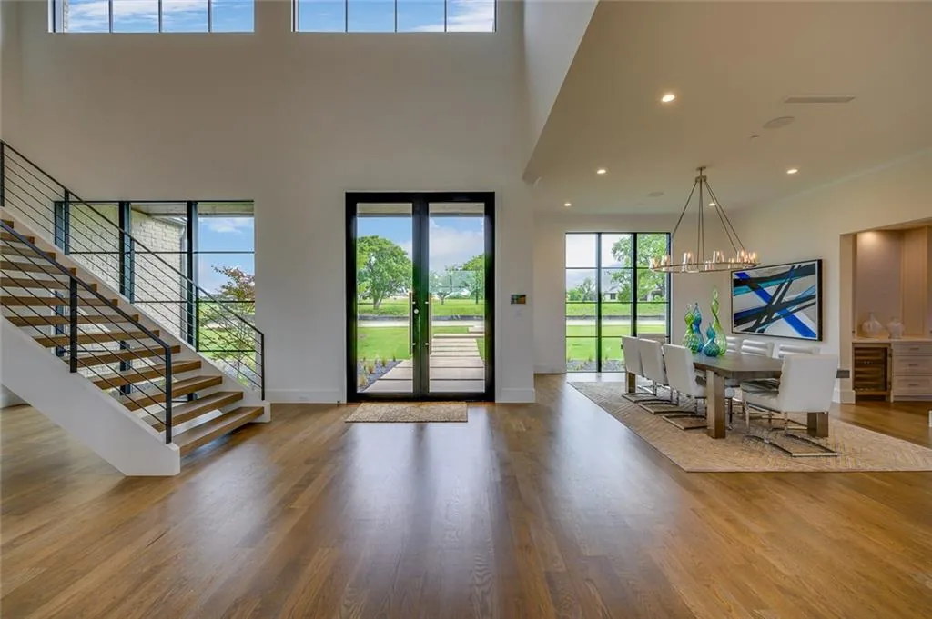 Two-story entry with an open stair and cable railing, glass front doors and a dining room under clerestory windows in Ridge Lakes of Heath